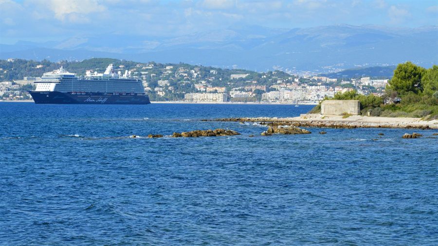Cruise ship sailing past a rocky shoreline